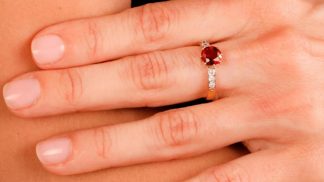 Striking round spinel ring with diamond-studded shoulders set in yellow gold, worn on a hand for a timeless, romantic look