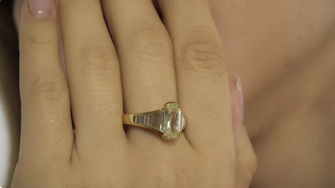 Close-up of a vintage yellow gold engagement ring with an elongated cushion cut diamond flanked by baguette diamond side accents.